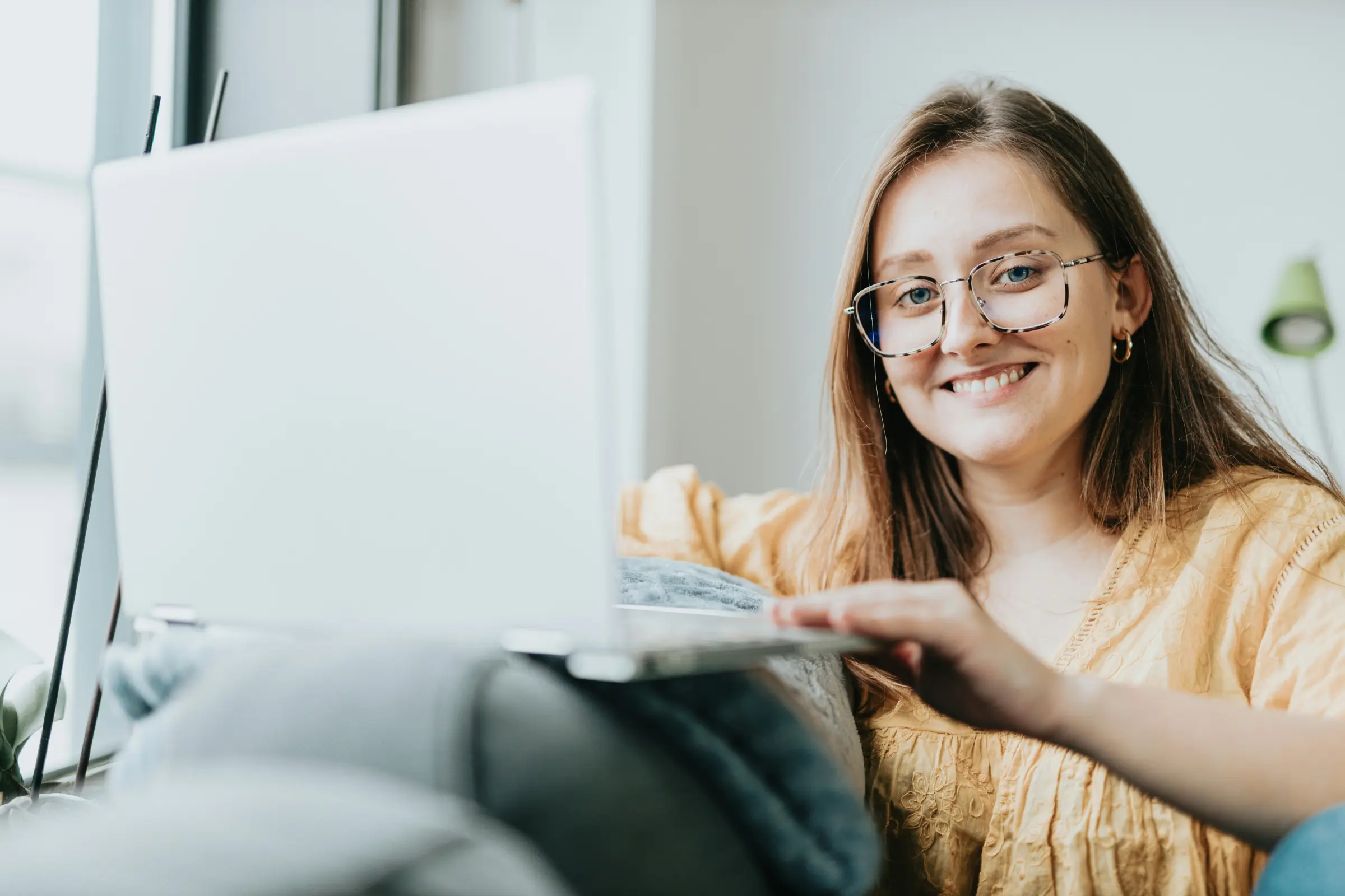 Woman in glasses smiling at her laptop at home