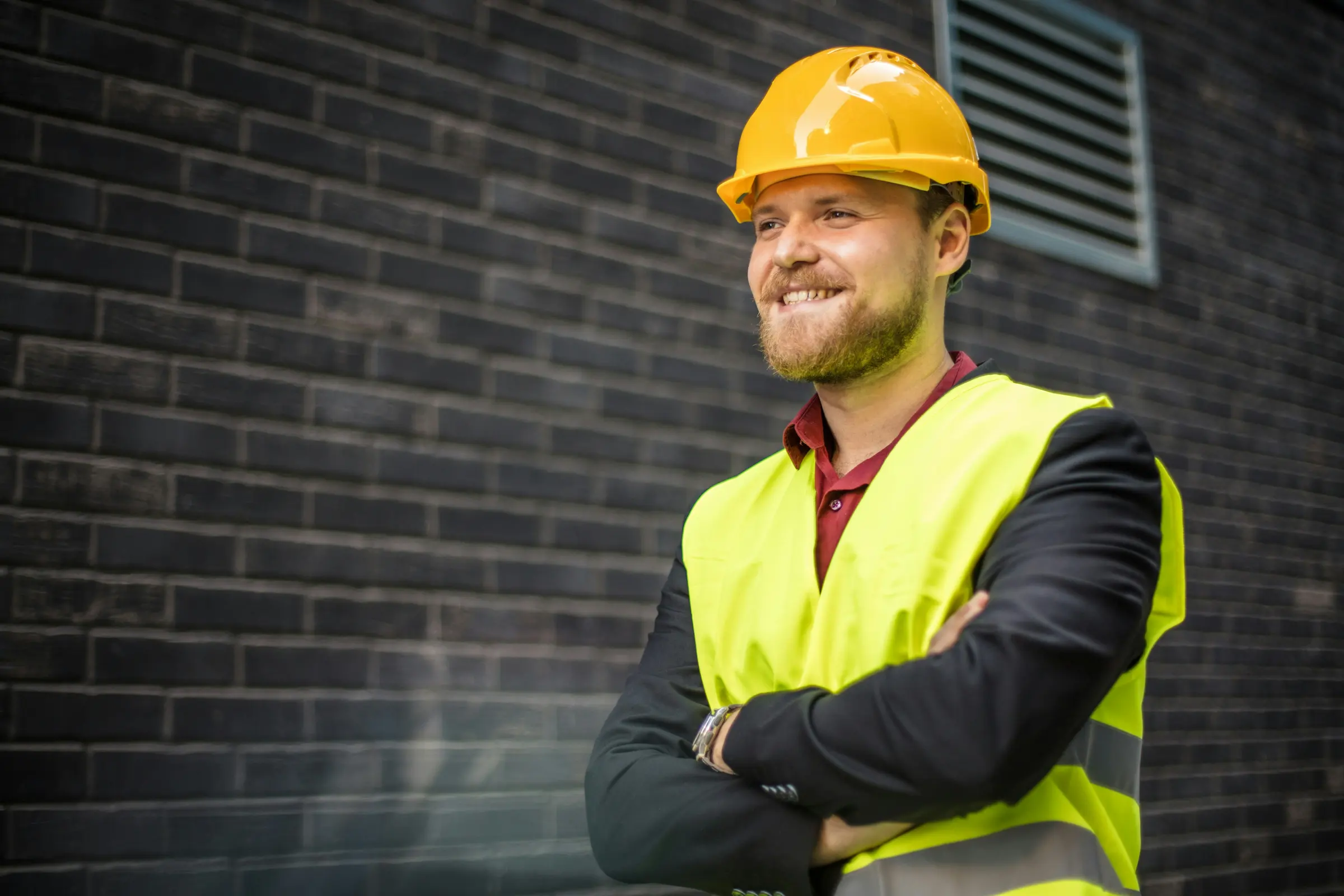 Worker in a hard hat and safety vest smiling