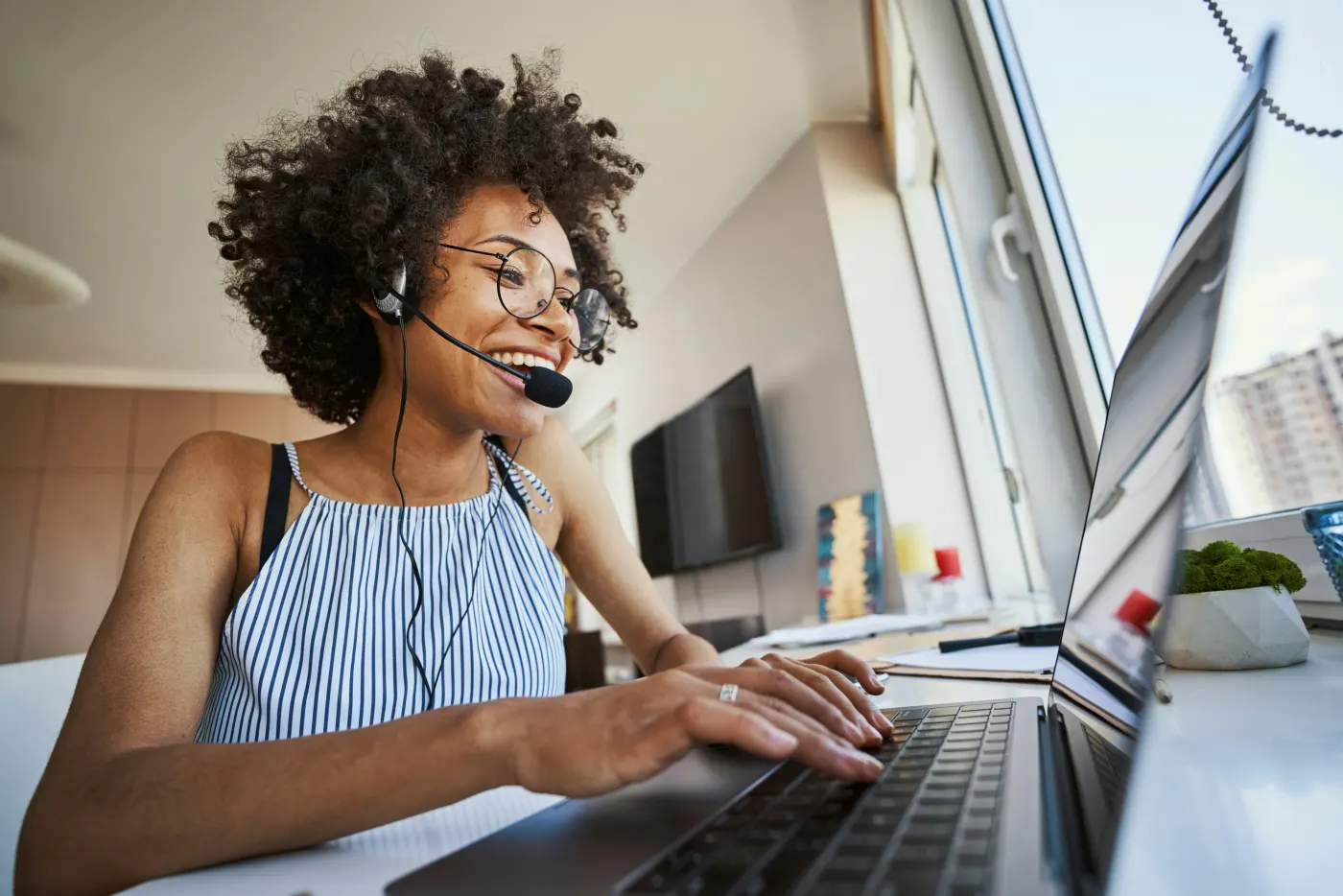 Admissions team member smiling on a headset at her laptop